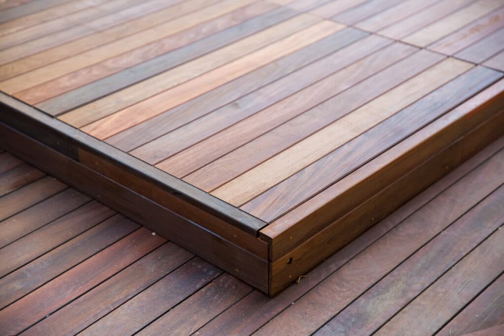 Terrasse en bois moderne à deux niveaux. Le deck supérieur clair contraste avec le plancher inférieur plus foncé.