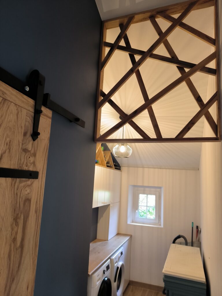 Luminosité chaleureuse dans une buanderie moderne avec porte coulissante effet grange, éclairage design et étagère à vin intégrée.