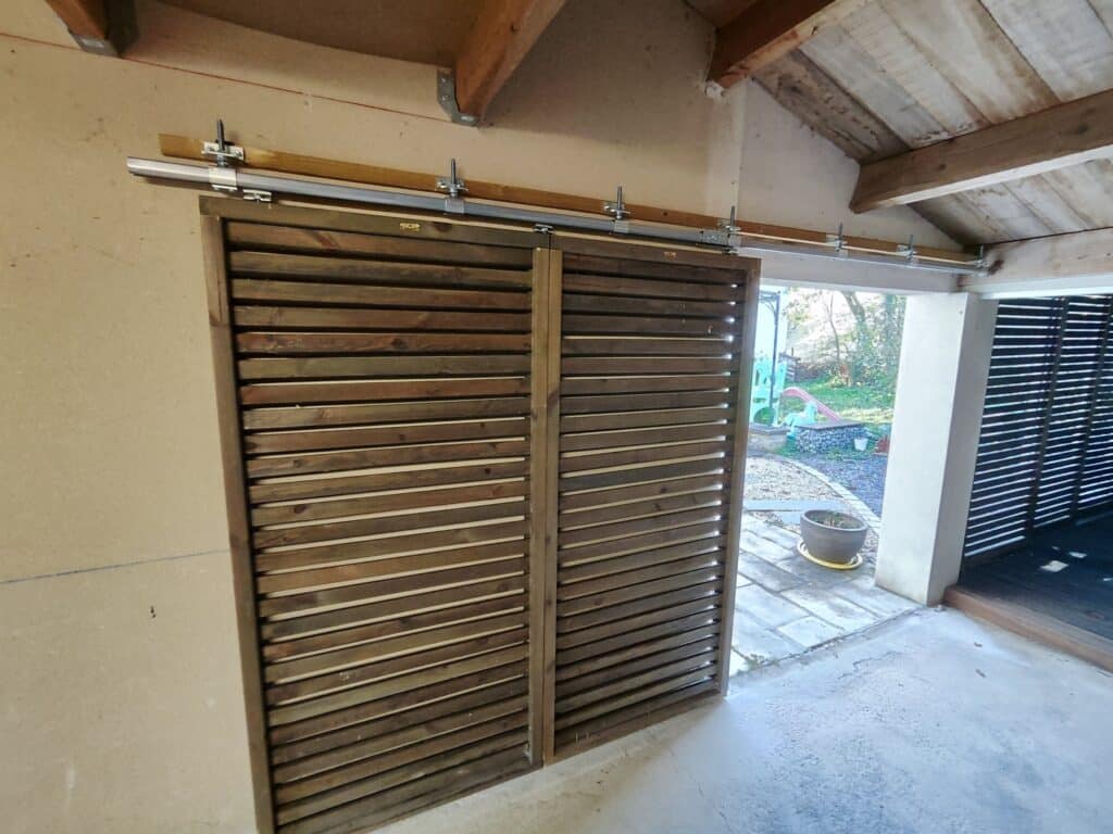 Porte coulissante en applique sur un rail métallique.