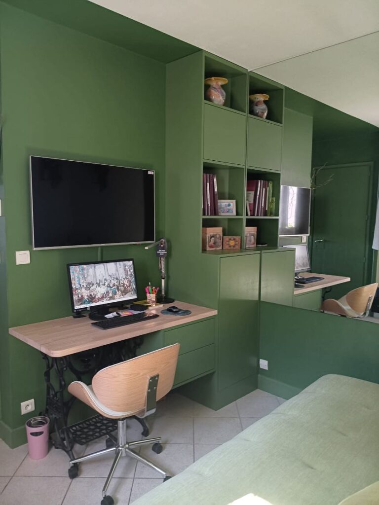 Bureau mural avec étagères vert sapin, bureau vintage en pied de machine à coudre et fauteuil scandinave moderne.